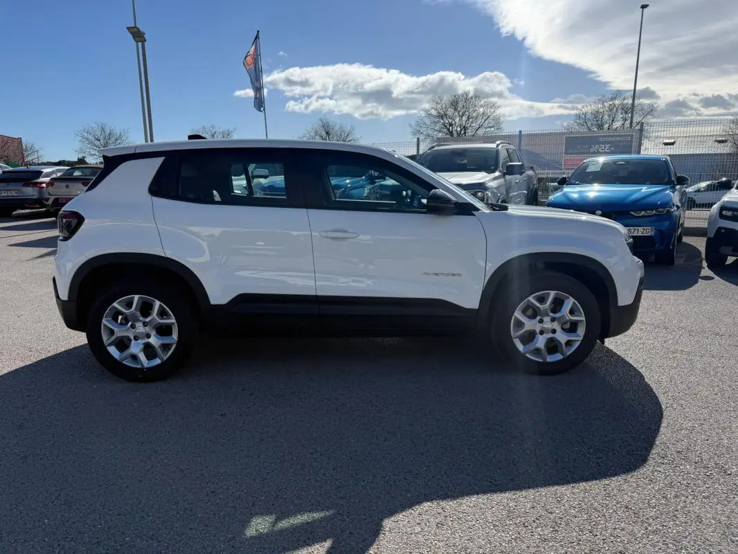 Jeep Avenger blanc vu de profil côté gauche, avec jantes alliage 17 pouces et toit noir contrasté.