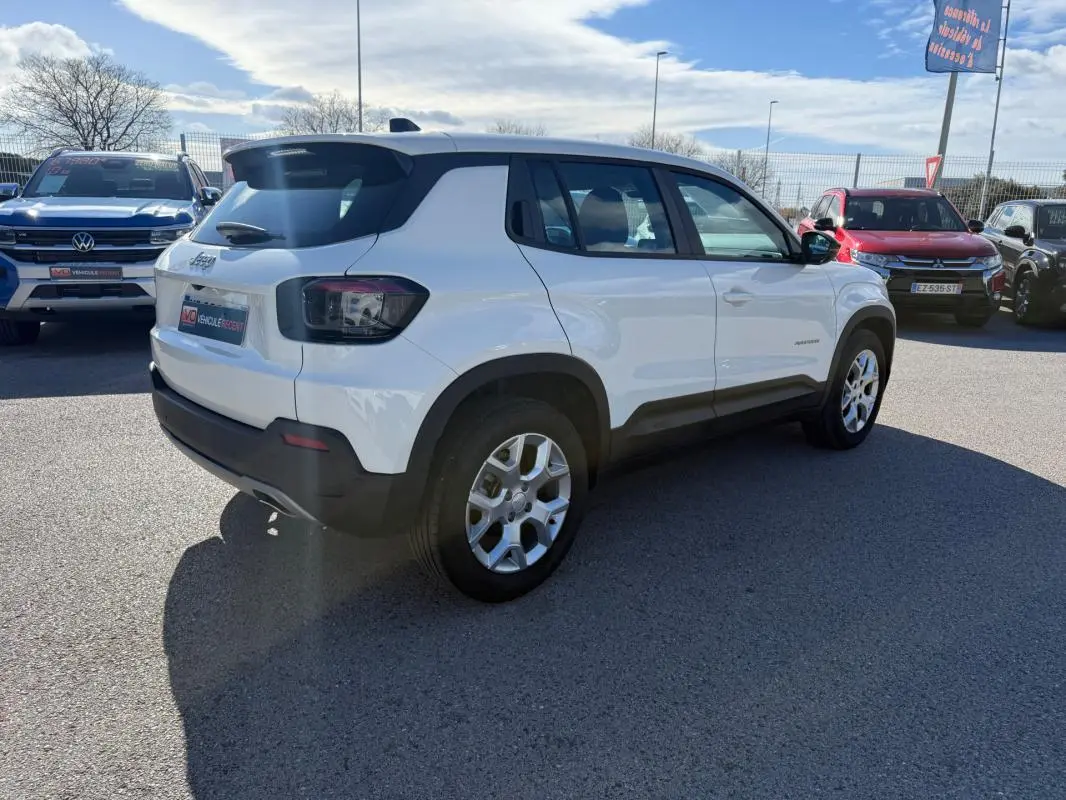 Jeep Avenger blanc en vue 3/4 arrière droit, avec jantes alliage 17 pouces et feux arrière fumés.