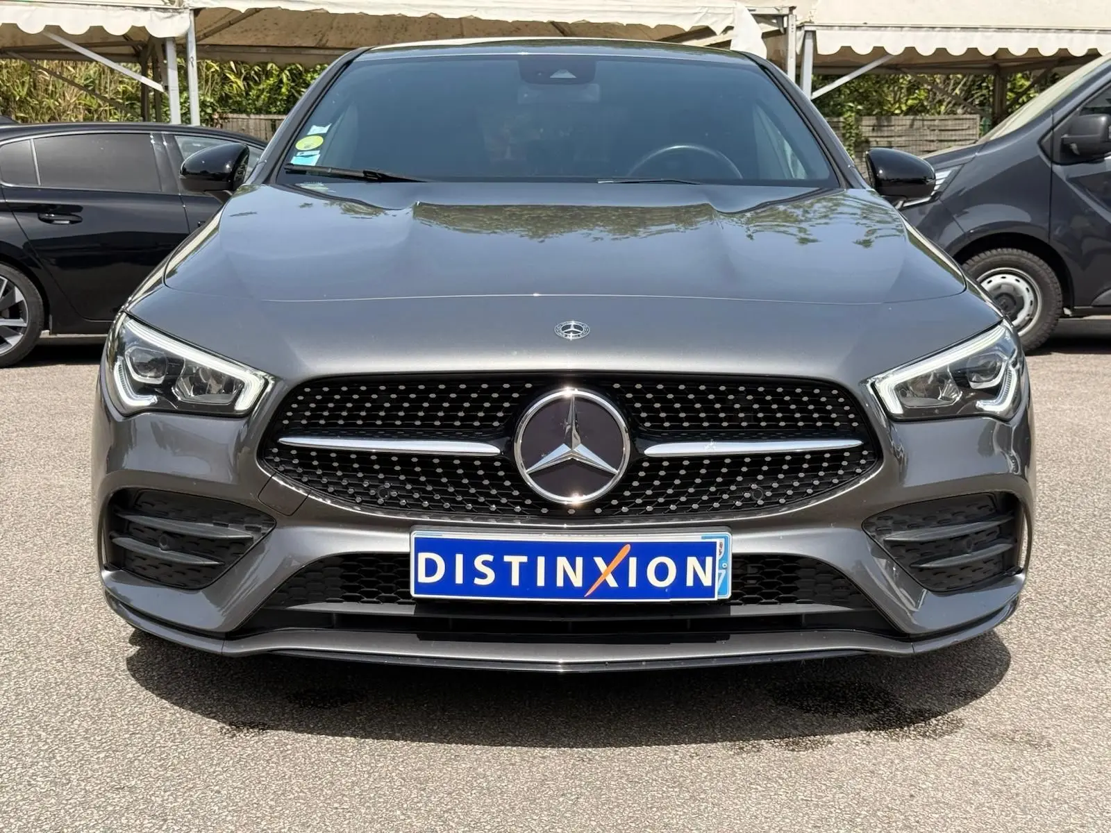 Vue avant d'une Mercedes Classe CLA 180 D AMG Line gris montagne avec calandre noire à motifs diamantés et logo central.