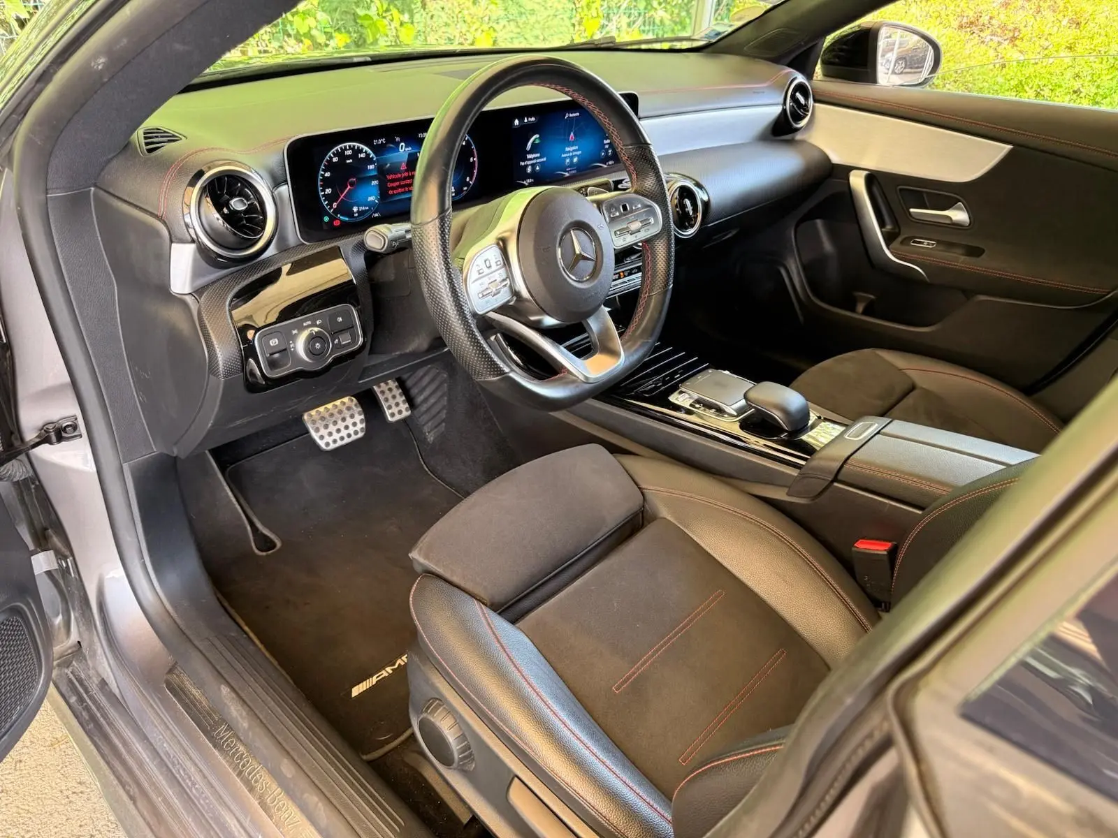 Vue intérieure côté conducteur de la Mercedes Classe CLA 180 D AMG Line 2019, avec volant sport et finitions cuir noir.