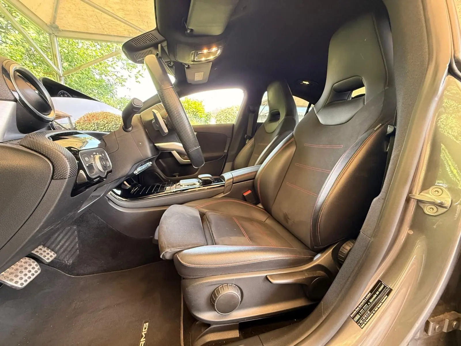 Intérieur côté conducteur de la Mercedes Classe CLA 180 D AMG Line 2019, sièges cuir noir avec surpiqûres rouges.