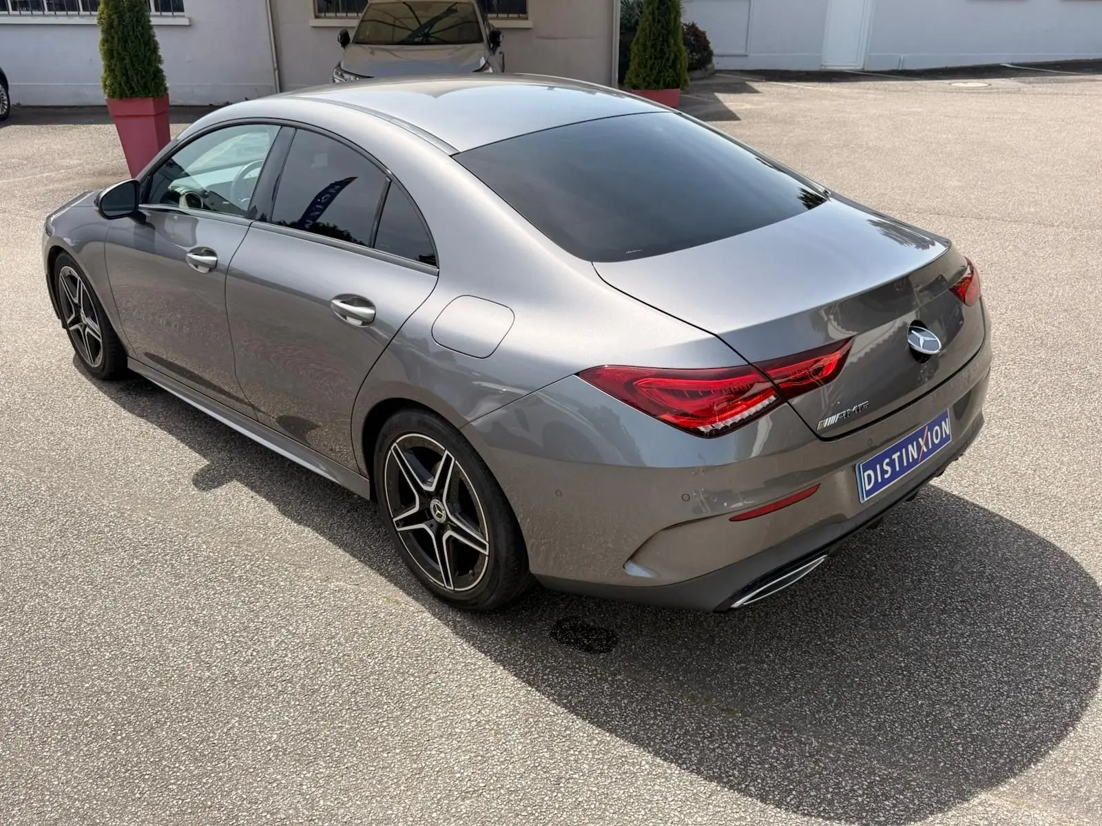 Vue 3/4 arrière droite d'une Mercedes Classe CLA 180 D AMG Line gris montagne avec jantes AMG et vitres teintées.