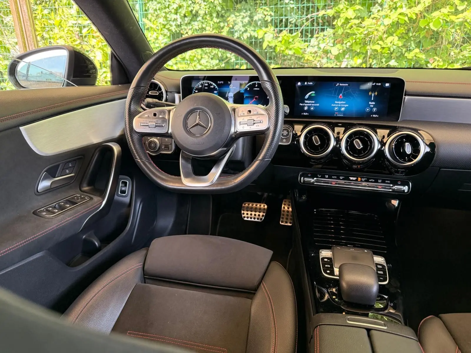 Vue intérieure avant du poste de conduite de la Mercedes Classe CLA 180 D AMG Line avec volant multifonction et écran digital large.