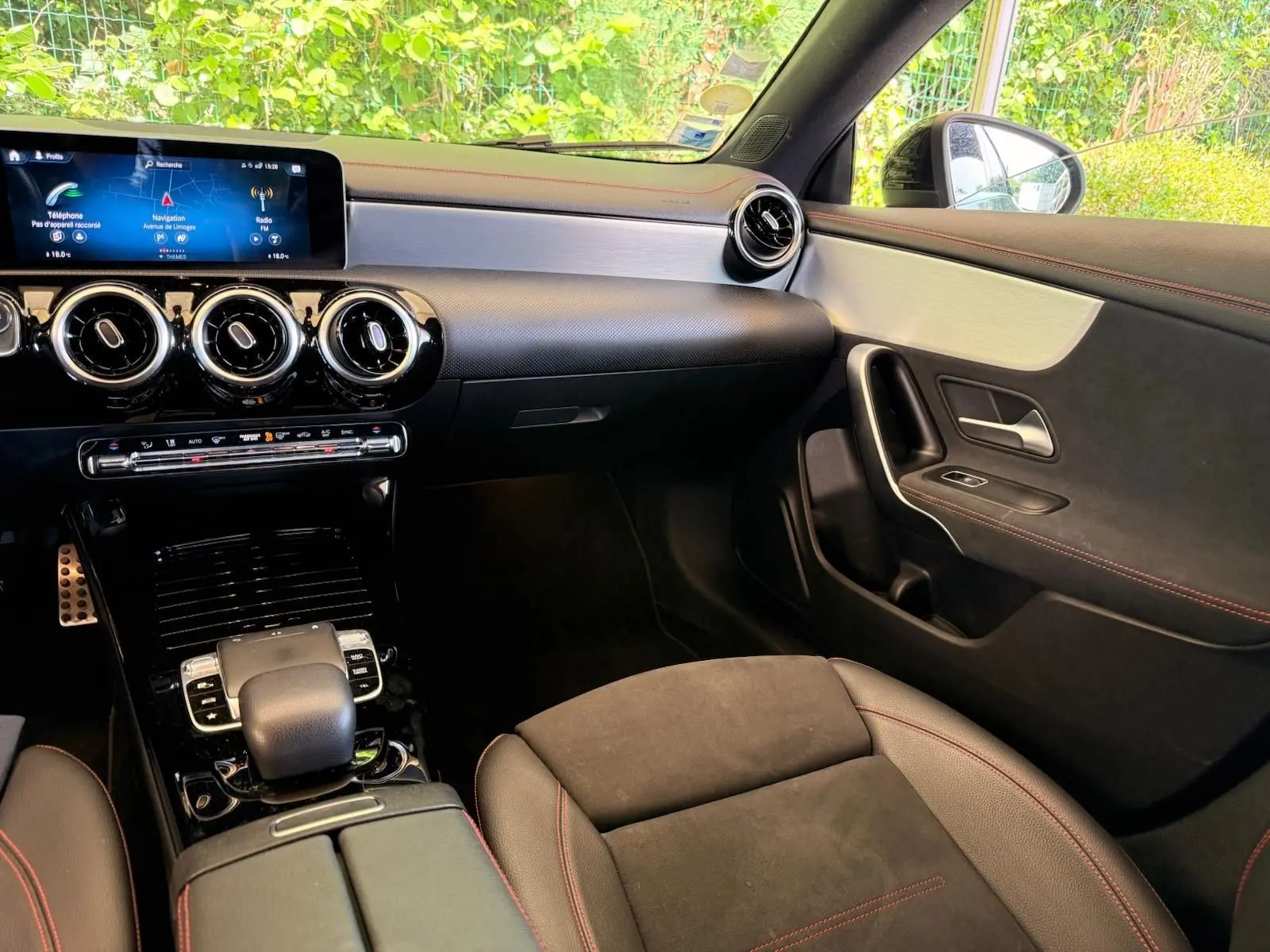 Vue intérieure côté passager de la Mercedes Classe CLA 180 D AMG Line 2019, avec tableau de bord noir et surpiqûres rouges.