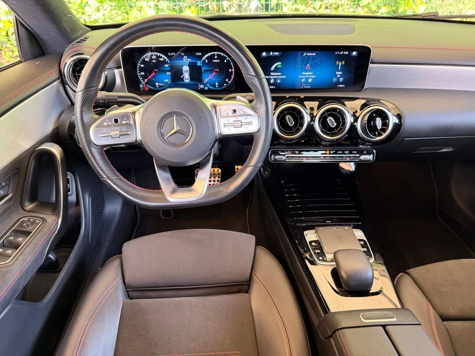 Vue intérieure avant de la Mercedes Classe CLA 180 D AMG Line 2019, volant cuir perforé et écran digital large.