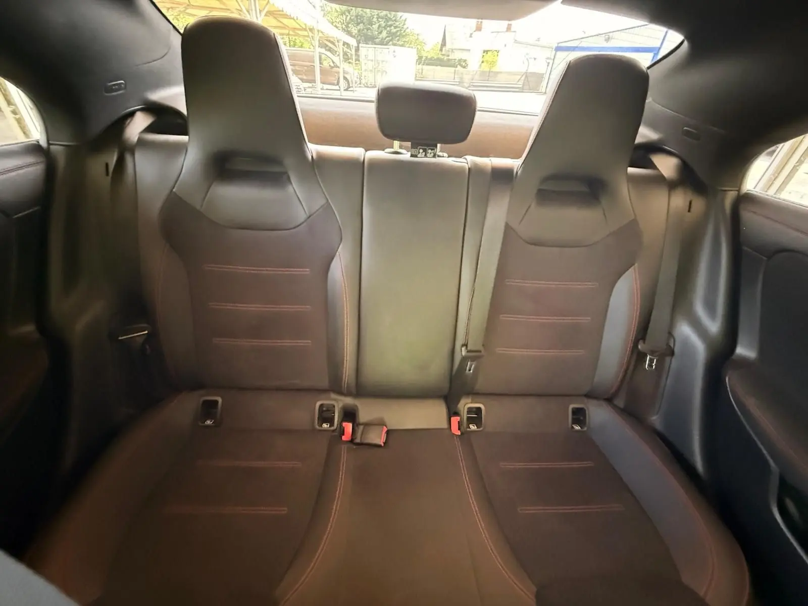 Vue intérieure arrière des sièges sport noirs avec surpiqûres rouges de la Mercedes CLA 180 D AMG Line 2019.