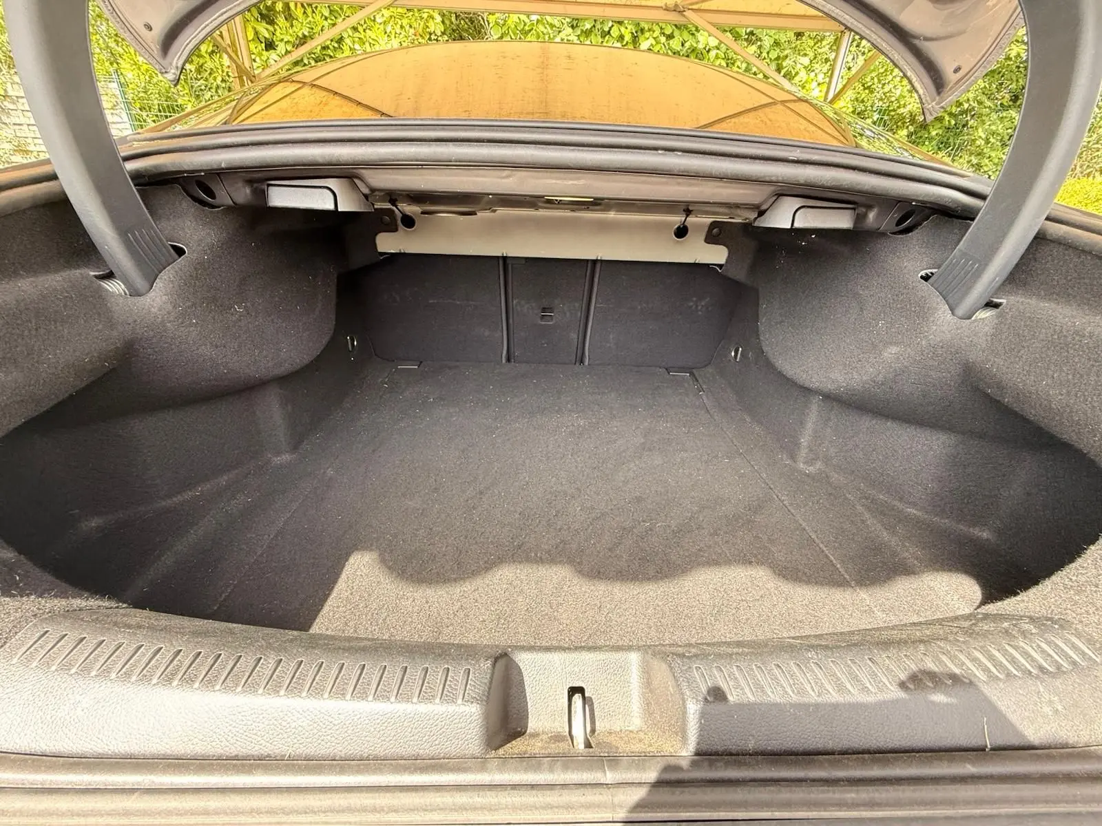 Coffre ouvert vu de l'arrière d'une Mercedes Classe CLA 180 D AMG Line gris montagne, espace de chargement vide et propre.