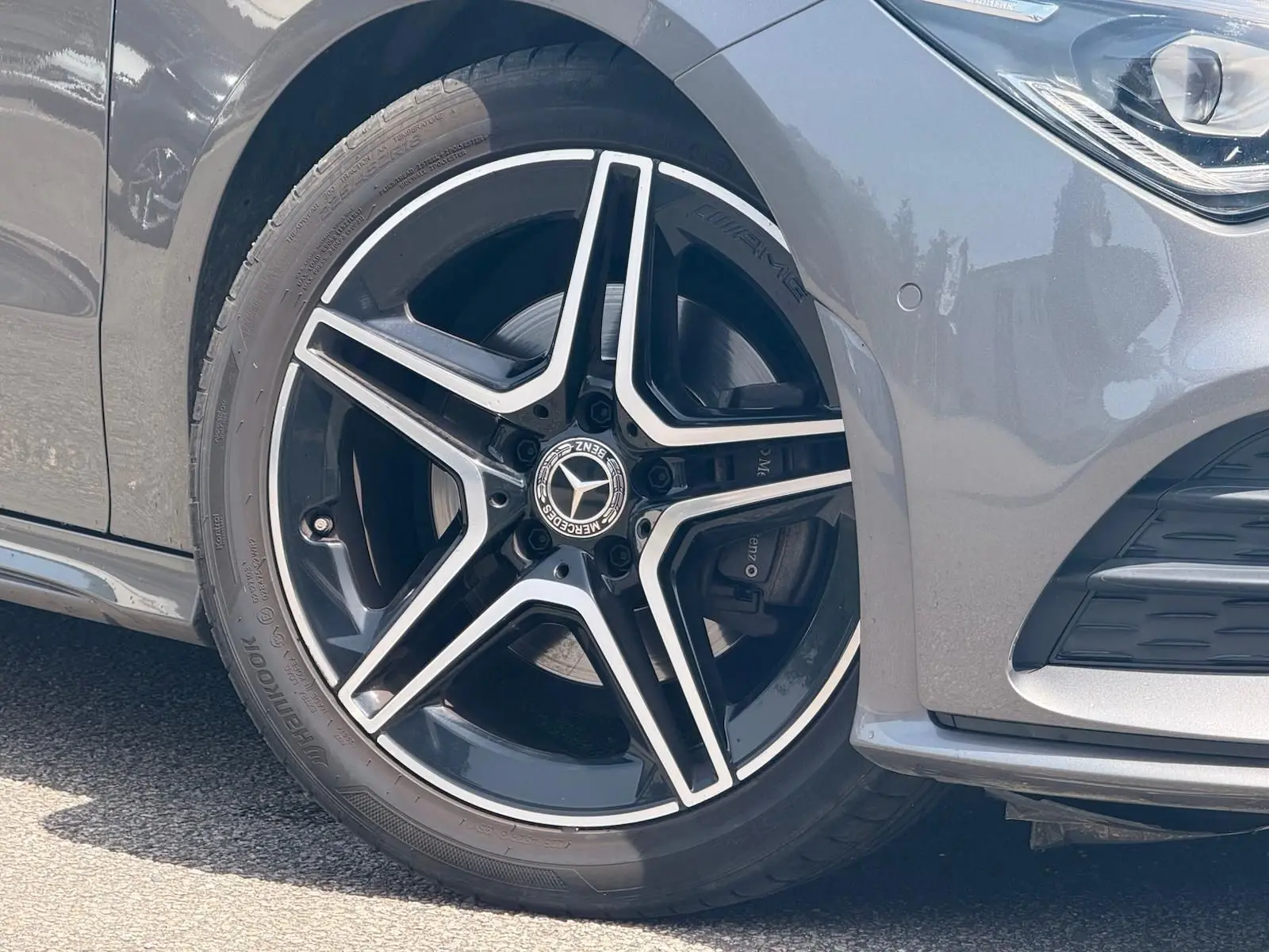 Gros plan sur la roue avant gauche d'une Mercedes CLA 180 D AMG Line gris montagne avec jante étoile noire et argent.