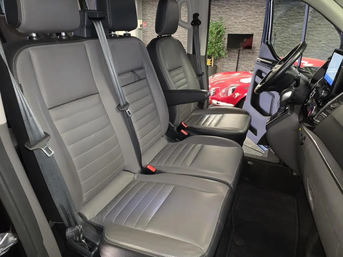 Vue intérieure côté conducteur du Ford Transit Fourgon Custom 2022, sièges cuir gris anthracite avec accoudoir.