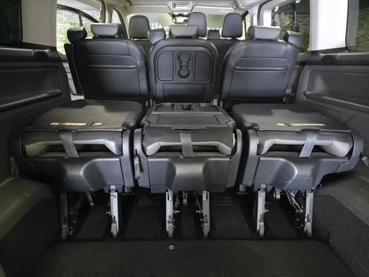Vue arrière intérieure du Ford Transit Custom noir 2022, sièges de 2e rangée rabattus et modulables en cuir gris anthracite.