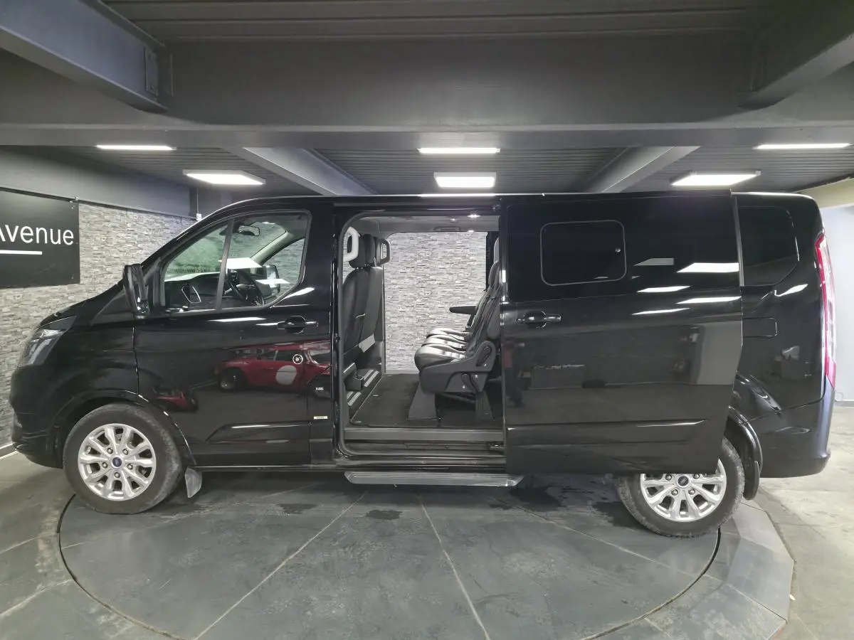 Vue de profil côté gauche d'un Ford Transit Fourgon noir 2022 avec porte coulissante ouverte et sièges passagers visibles.