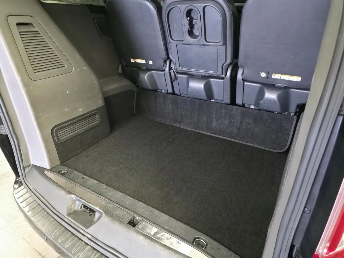 Vue arrière de l'espace de chargement noir du Ford Transit Fourgon Custom avec sièges arrière rabattus.