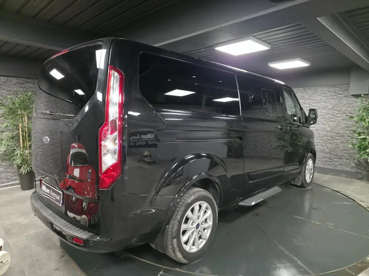 Ford Transit Fourgon Custom noir, vue 3/4 arrière droit, vitres teintées et jantes alliage 17 pouces visibles.