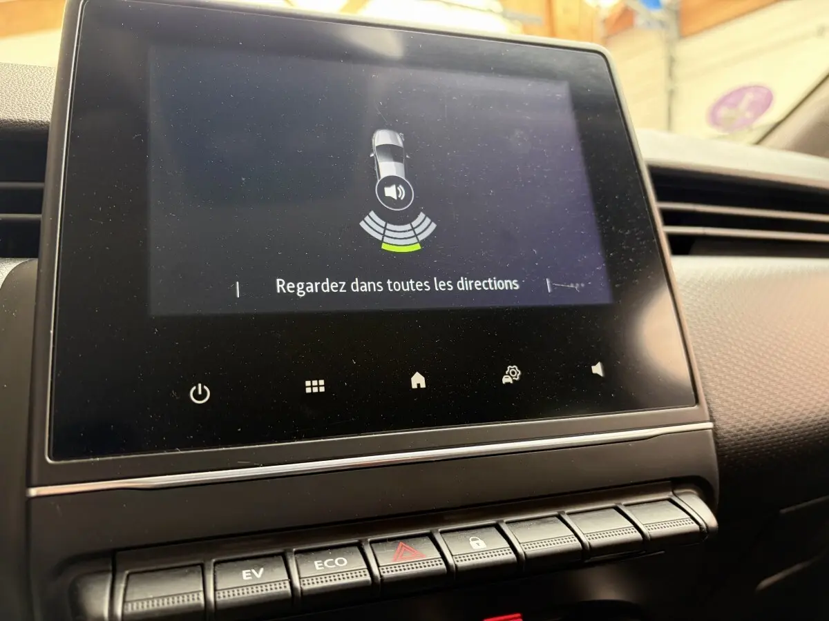 Écran tactile central affichant l'aide au stationnement dans l'habitacle de la Renault Clio Business E-Tech hybride blanc.