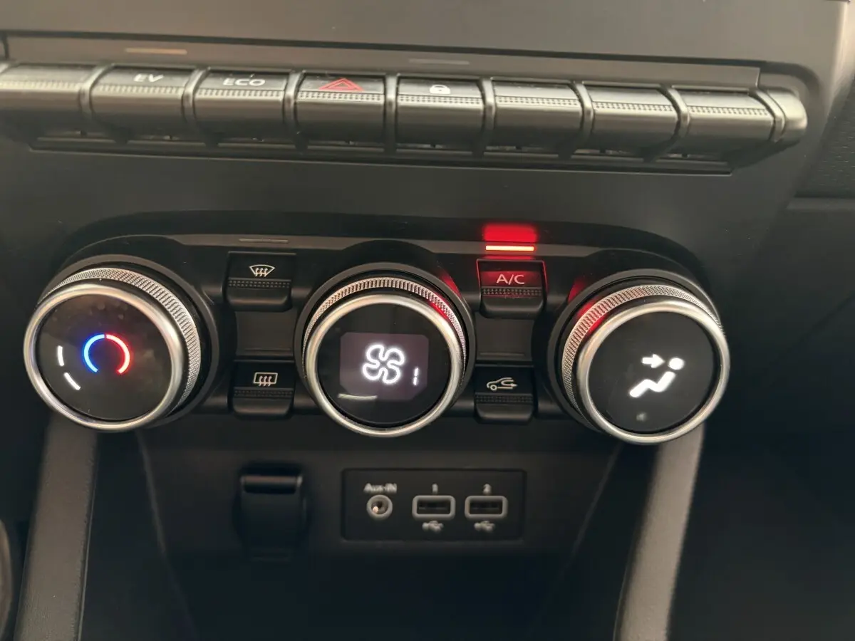 Gros plan sur les commandes de climatisation et ports USB de la Renault Clio Business E-Tech hybride blanc, tableau de bord central.