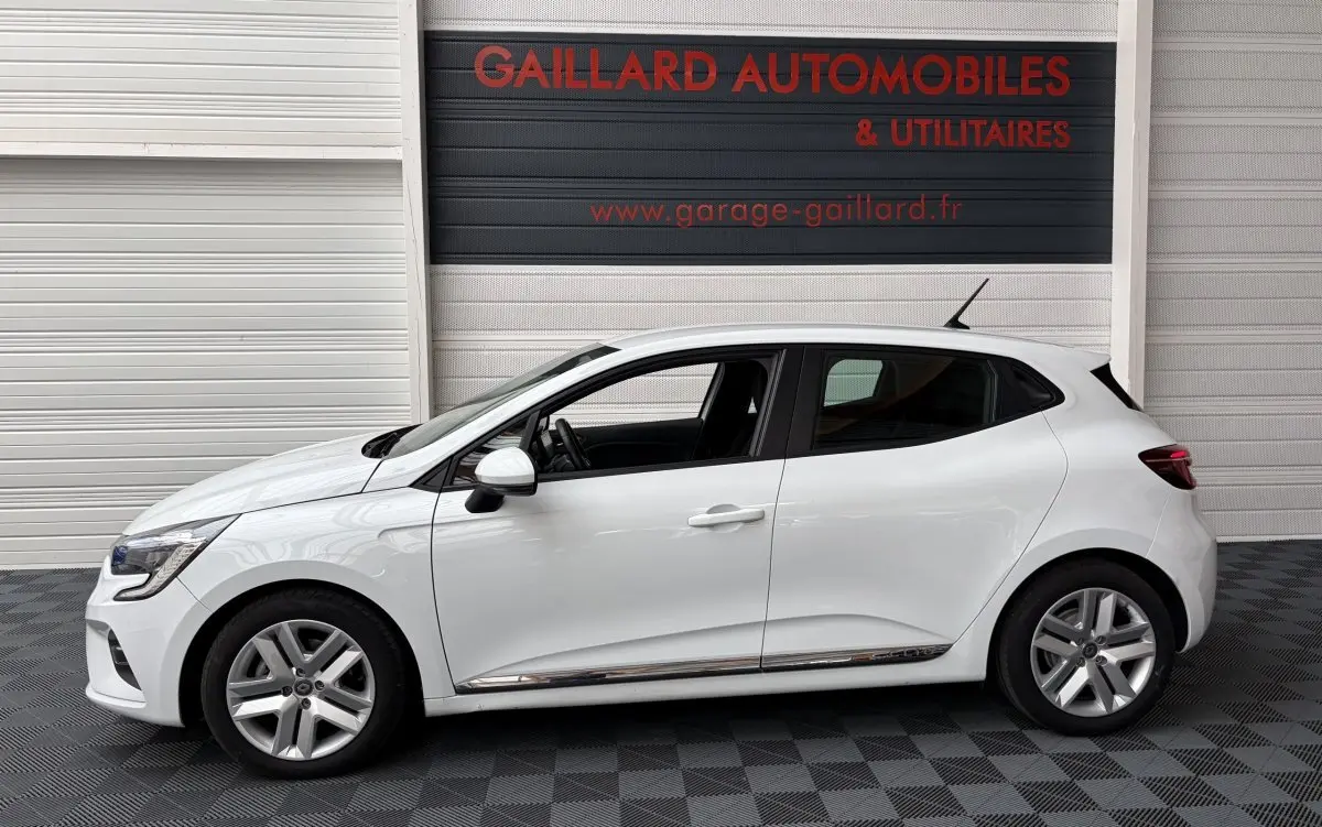 Profil côté gauche d'une Renault Clio Business E-Tech hybride blanche 2022, avec jantes alliage et rétroviseur blanc.