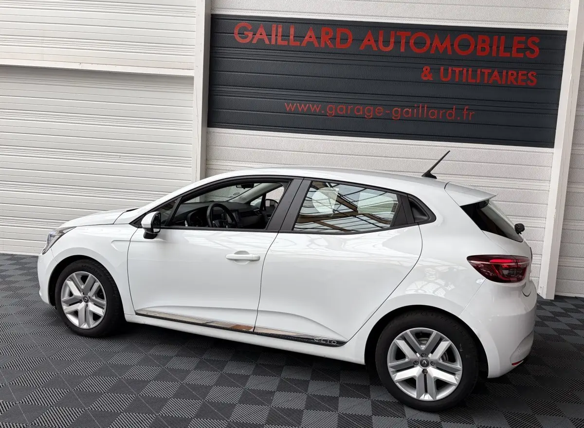 Profil droit d'une Renault Clio Business E-Tech hybride blanche 2022, avec jantes alliage et vitres teintées.