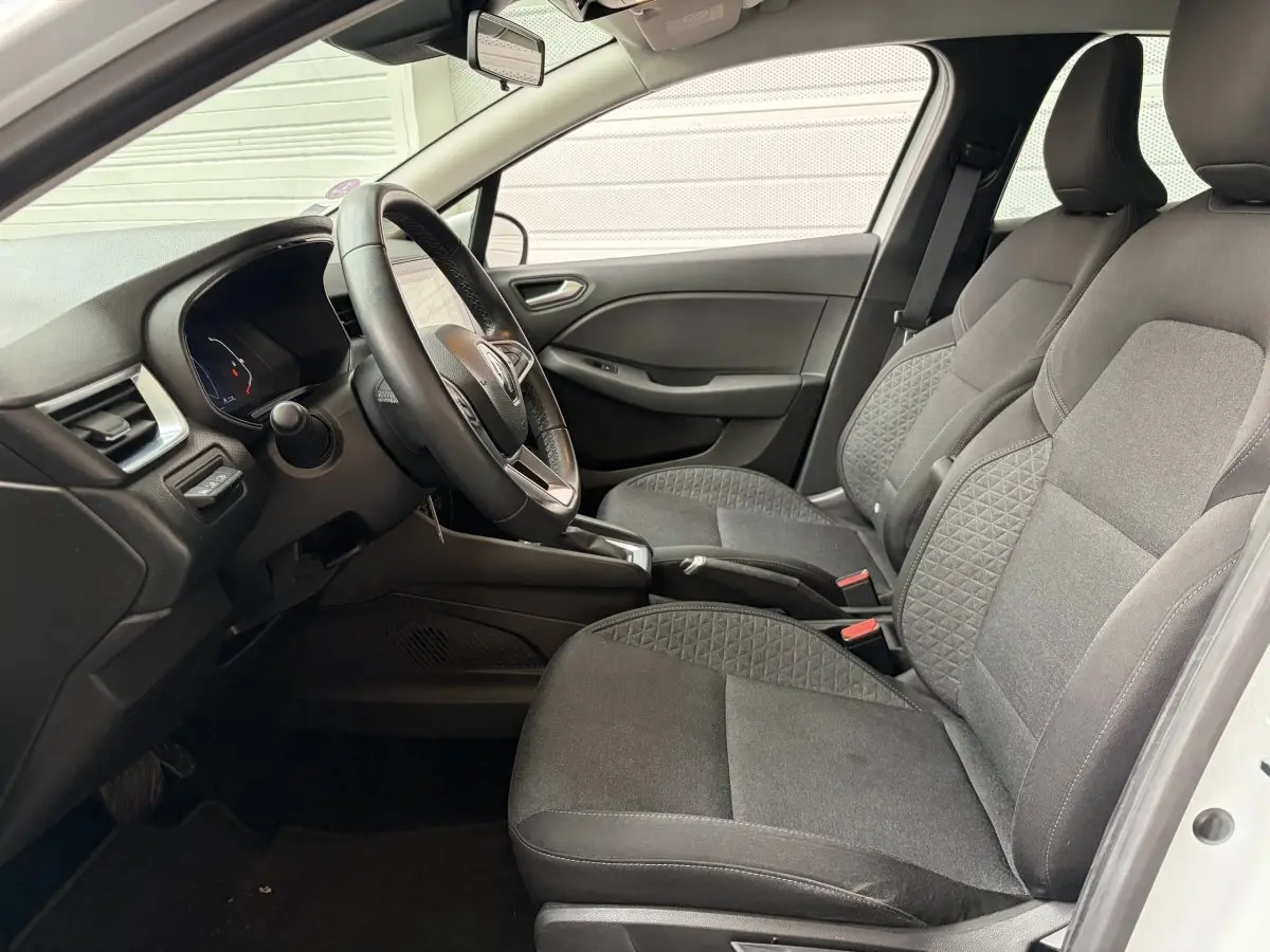 Vue intérieure côté conducteur de la Renault Clio Business E-Tech hybride 2022, sièges tissu gris et volant multifonctions cuir synthétique.