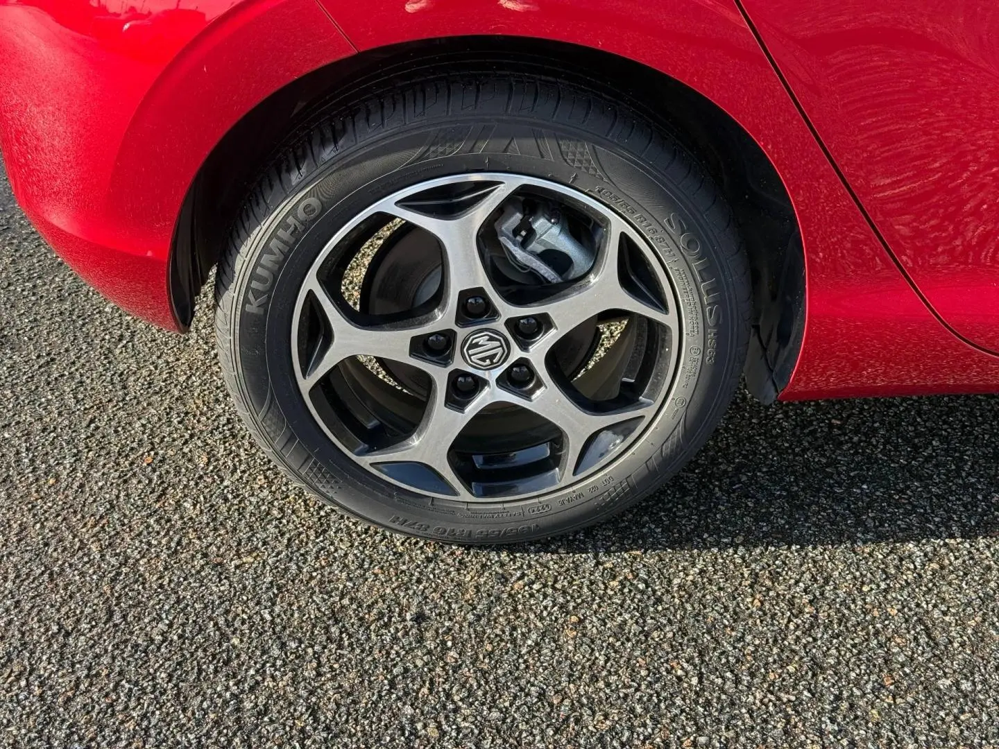 Gros plan sur la roue avant droite du MG3 1.5 Hybrid+ Luxury en rouge Diamond Red métallisé, jante alu à cinq branches.