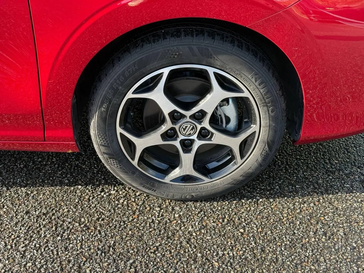 Gros plan sur la roue avant droite avec jante alu cinq branches du MG3 1.5 Hybrid+ Diamond Red métallisé.