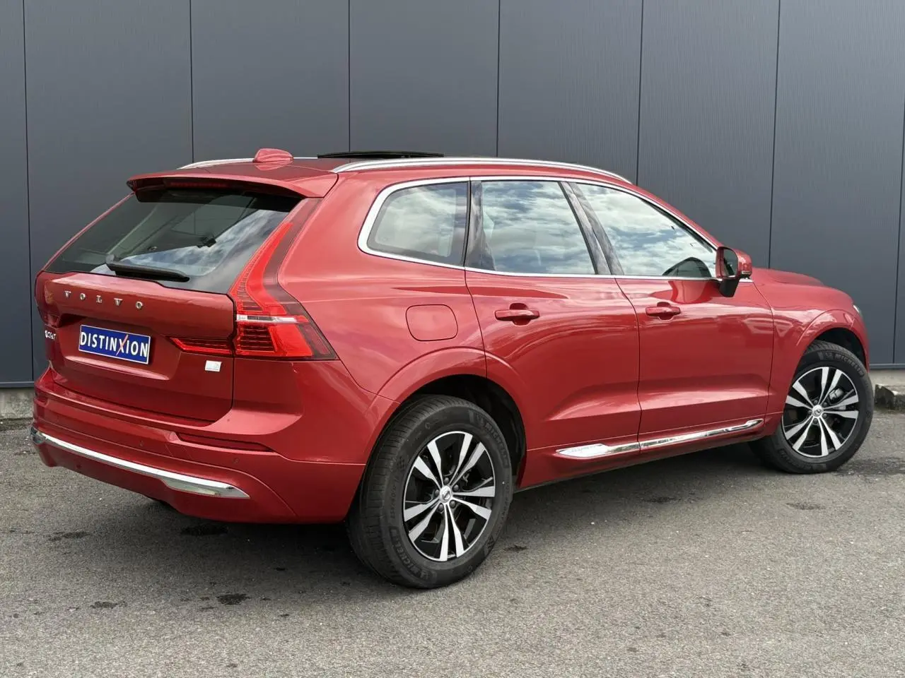 Vue 3/4 arrière droite d'un Volvo XC60 rouge Fusion avec jantes alliage et contours chromés des vitres