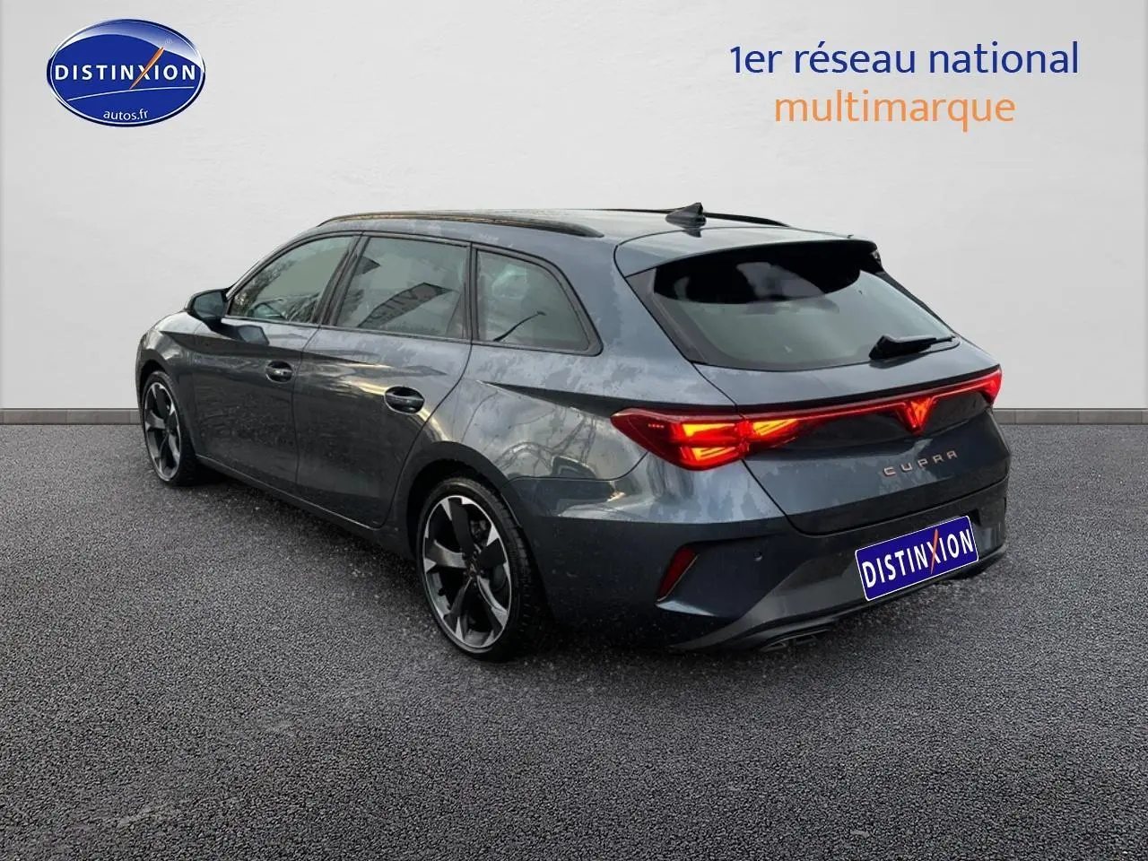 Vue 3/4 arrière droite d'une CUPRA LEON ST gris magnétique avec feux arrière LED allumés et jantes alliage noires.