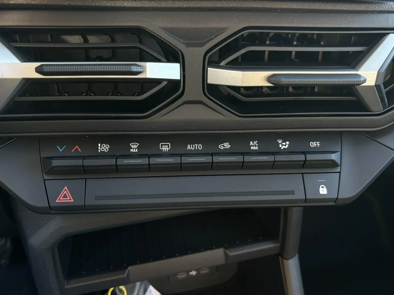 Gros plan sur la console centrale du Dacia Duster blanc Glacier, montrant les commandes de climatisation et les aérateurs noirs.