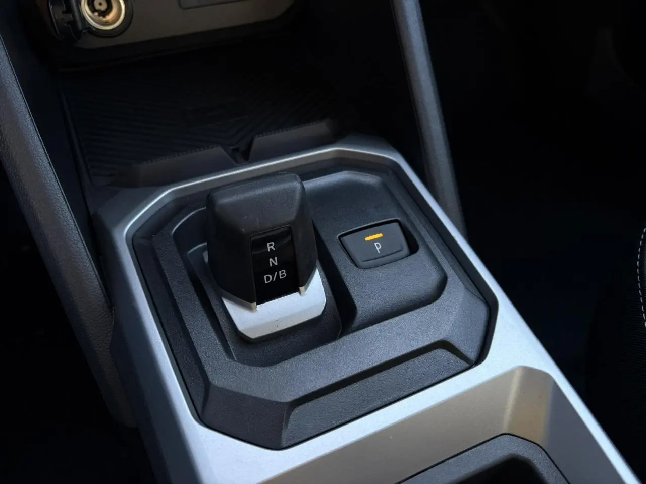 Gros plan sur la console centrale du Dacia Duster blanc Glacier 2025, montrant le levier de vitesses automatique et le bouton de parking.