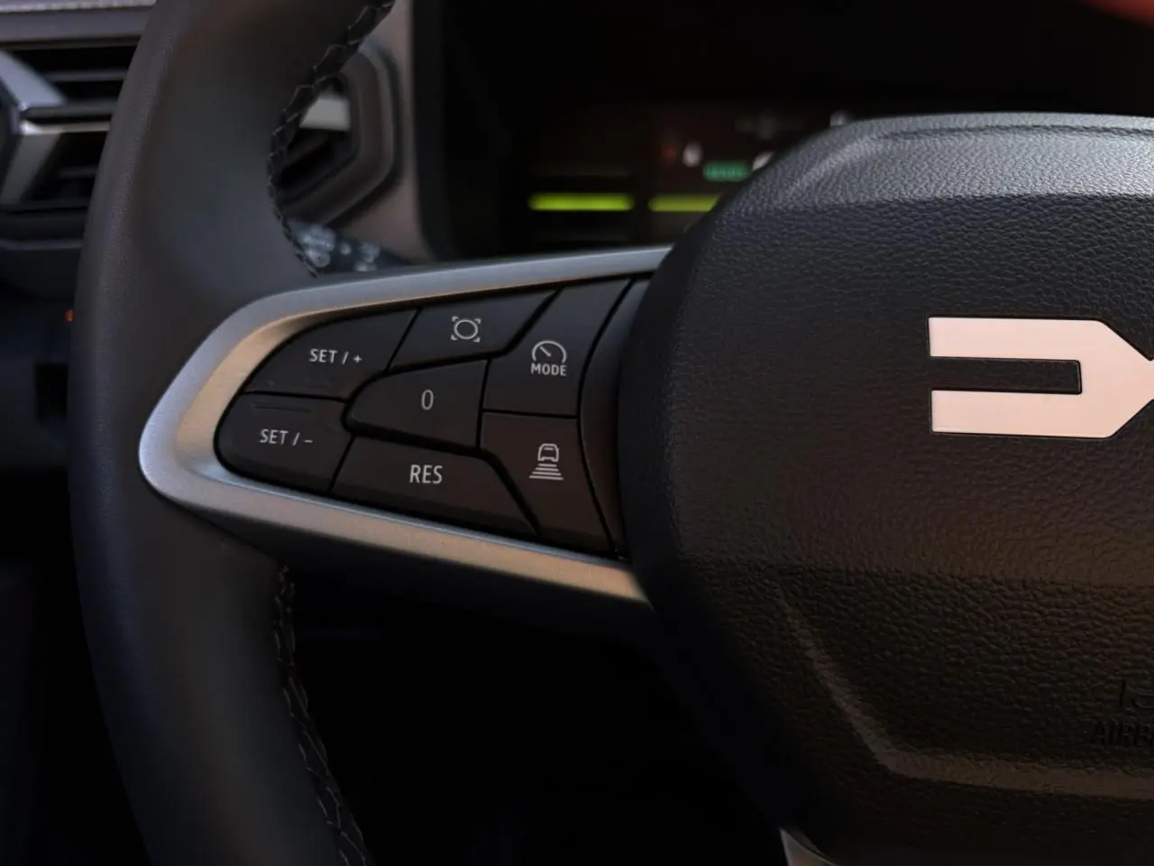 Gros plan sur le volant noir du Dacia Duster 2025, montrant les commandes de régulateur de vitesse côté gauche.