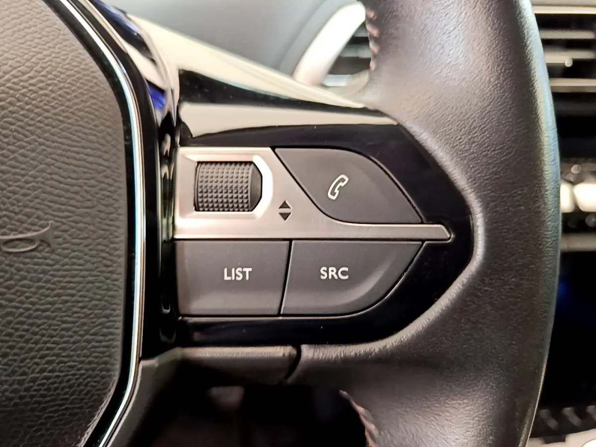 Gros plan sur les commandes gauche du volant cuir du Peugeot 3008 gris foncé, boutons LIST, SRC et téléphone.