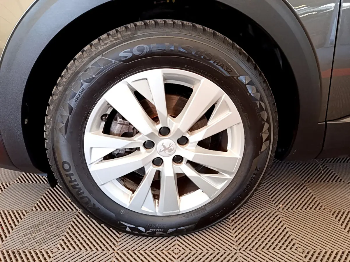 Gros plan sur la roue avant gauche du Peugeot 3008 gris foncé, mettant en valeur la jante alliage et le pneu Kumho.