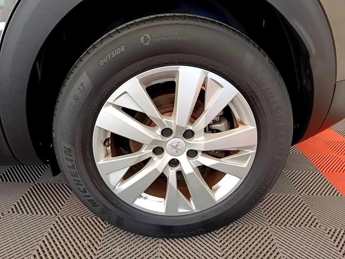 Gros plan sur la roue avant gauche du Peugeot 3008 gris foncé, avec jante alliage et pneu Michelin visible.