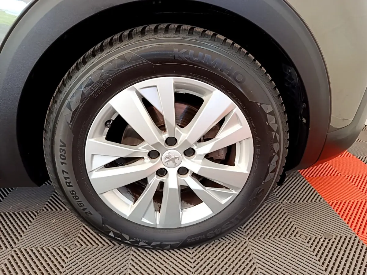 Gros plan sur la roue avant gauche du Peugeot 3008 gris foncé, mettant en valeur la jante alliage et le pneu Kumho.