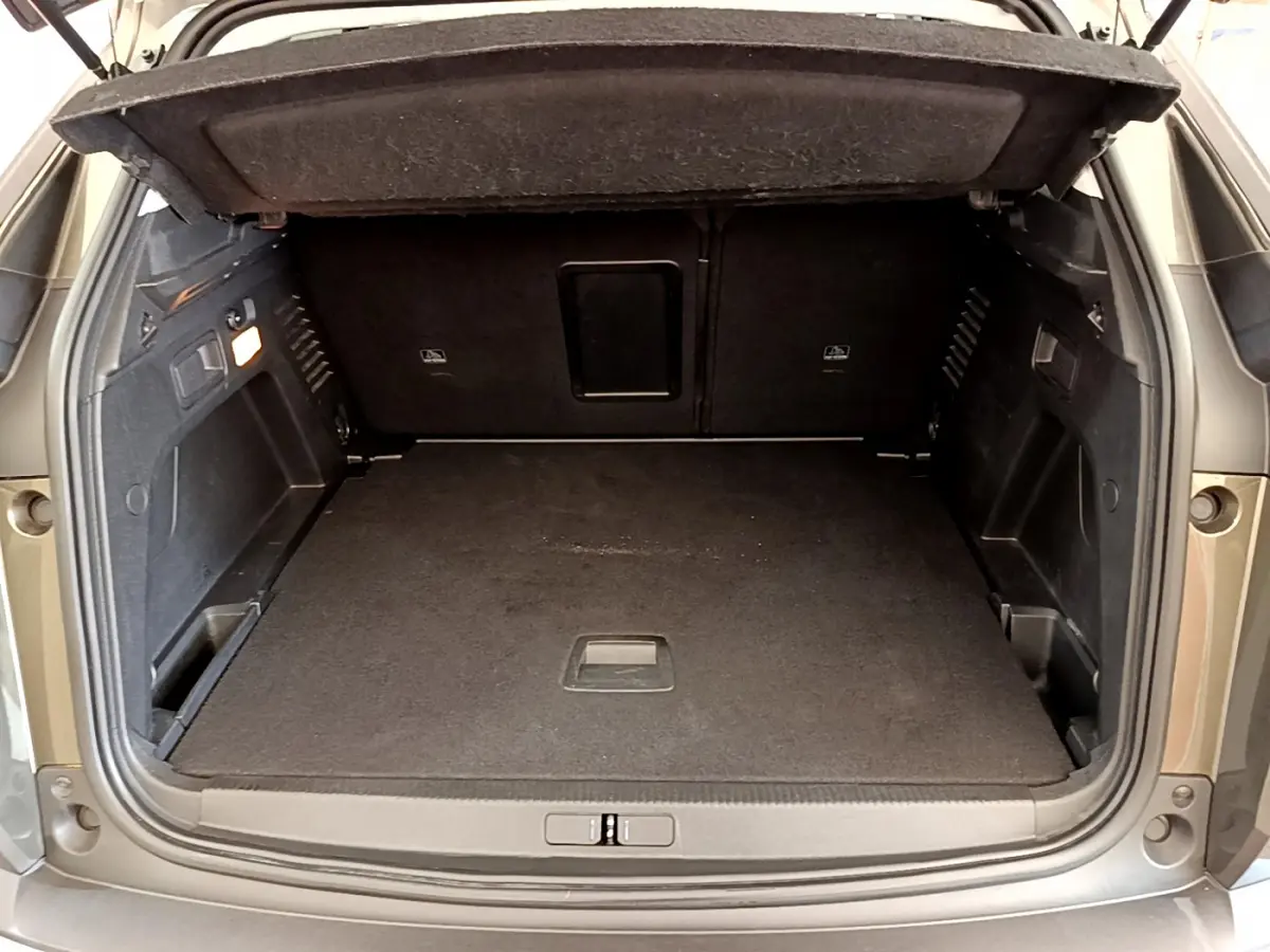 Coffre ouvert du Peugeot 3008 gris foncé, vue arrière montrant l'espace de chargement et la banquette rabattue.