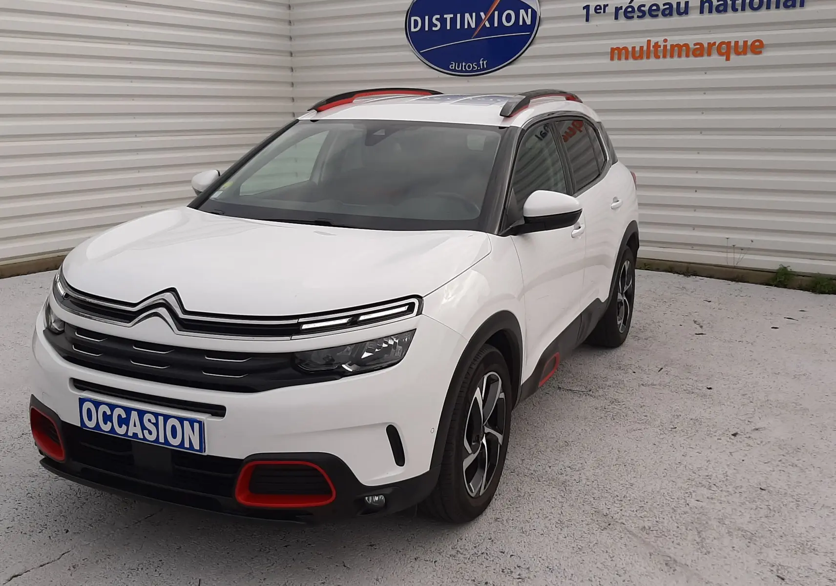 Citroën C5 Aircross blanc en 3/4 avant droit, avec détails rouges sur boucliers et jantes bicolores.