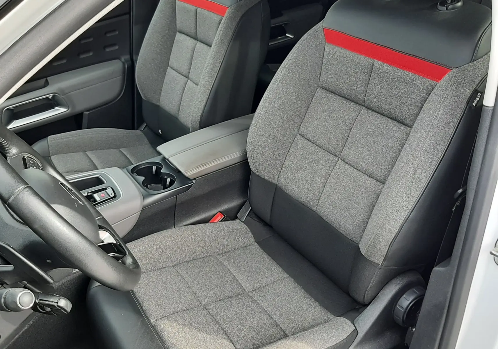 Vue intérieure côté conducteur du Citroën C5 Aircross blanc 2020, sièges gris avec bande rouge et console centrale.