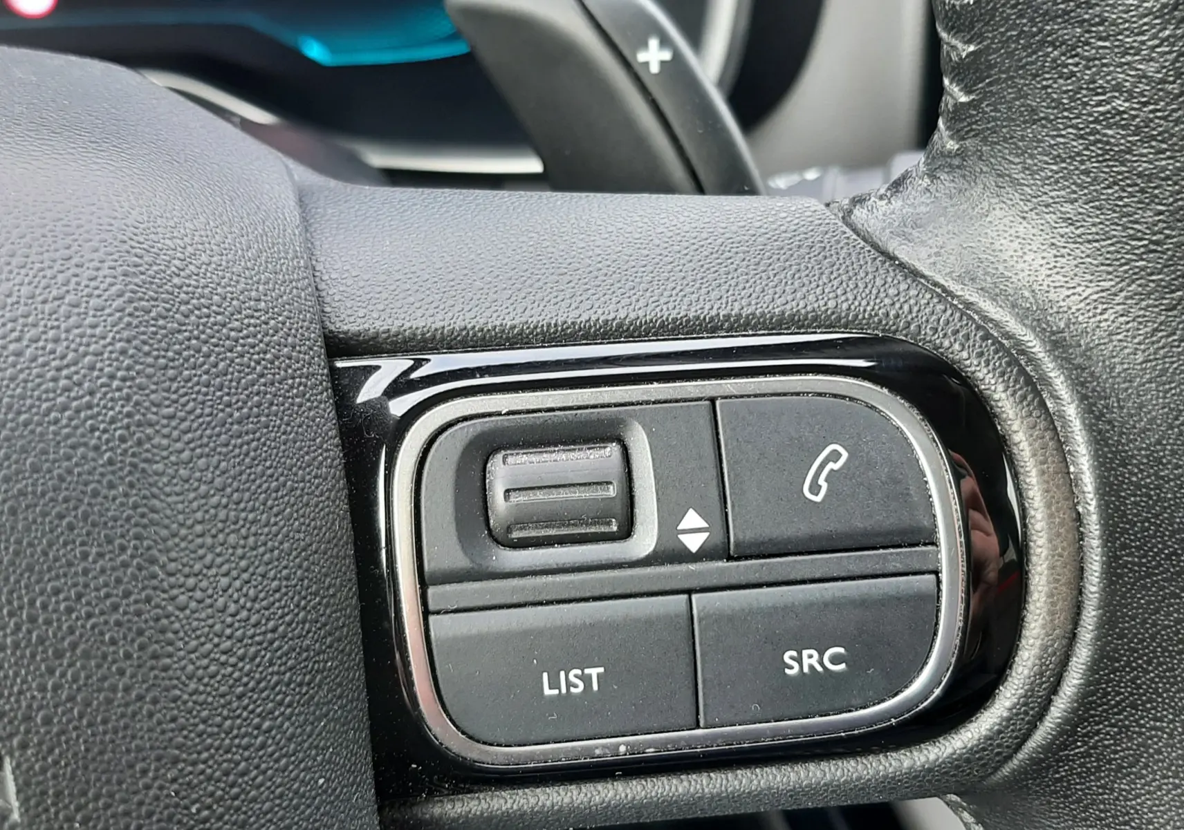 Gros plan sur les commandes noires du volant en cuir d’un Citroën C5 Aircross blanc, version BlueHDi 130ch Feel 2020.