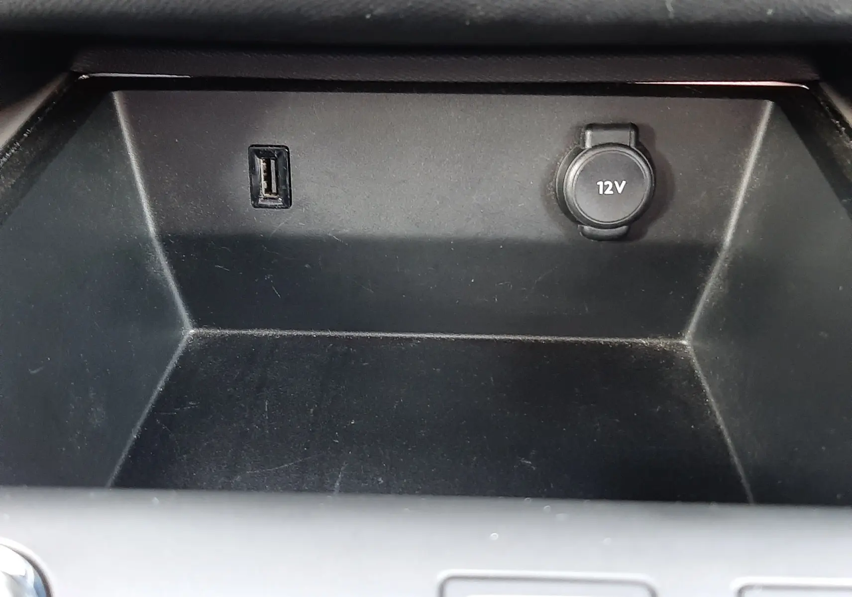 Gros plan sur la prise USB et la prise 12V dans le compartiment de rangement intérieur du Citroën C5 Aircross blanc.