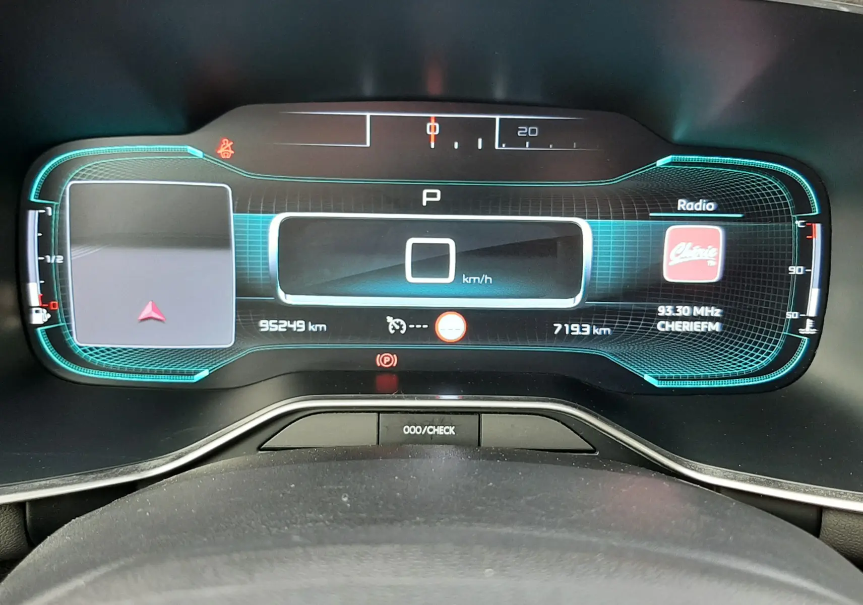 Vue rapprochée du tableau de bord numérique du Citroën C5 Aircross blanc, affichant la vitesse à 0 km/h et la radio allumée.