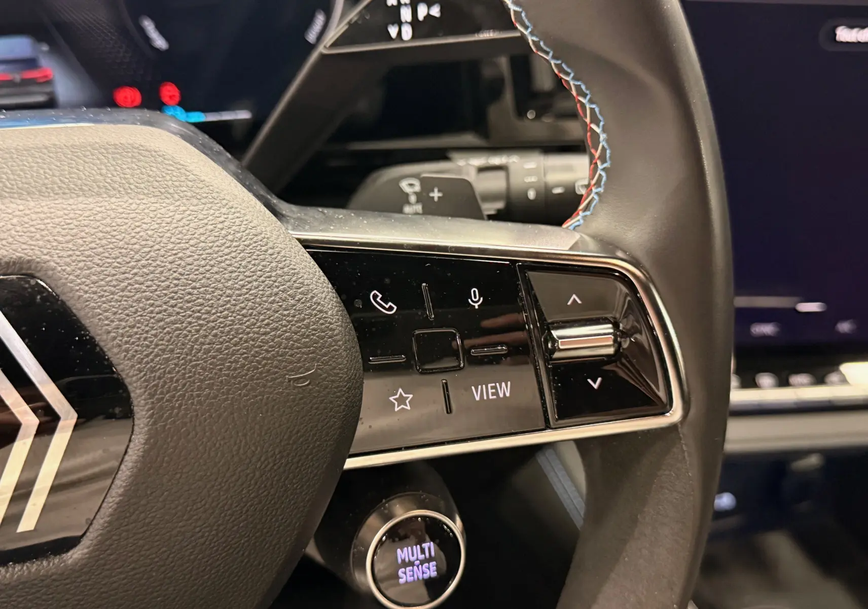 Gros plan sur la partie droite du volant noir du Renault Austral 2023, avec commandes tactiles et surpiqûres tricolores.