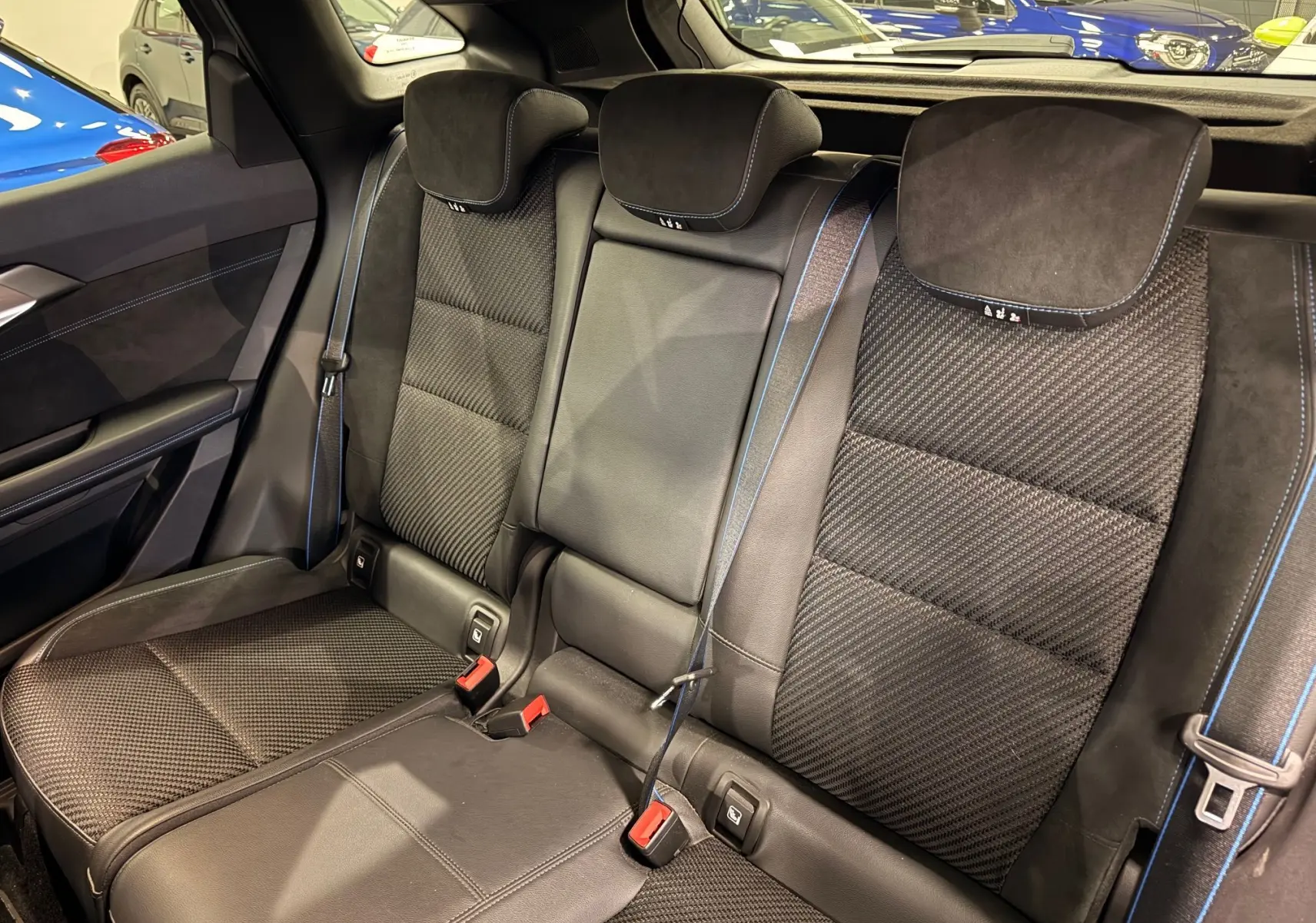 Vue intérieure des sièges arrière du Renault Austral E-Tech 2023, tissu noir avec surpiqûres bleues et appuie-têtes intégrés.