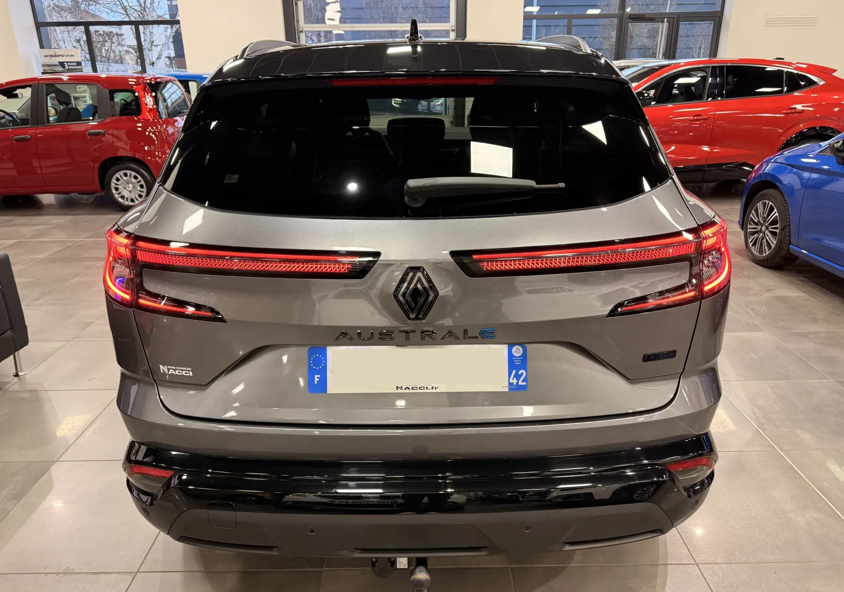 Vue arrière du Renault Austral gris schist avec toit noir, feux LED allumés et logo distinctif au centre.