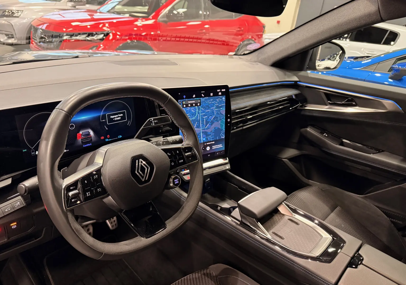 Vue intérieure côté conducteur du Renault Austral E-Tech 2023, tableau de bord numérique et écran central tactile avec ambiance noire et détails bleus.