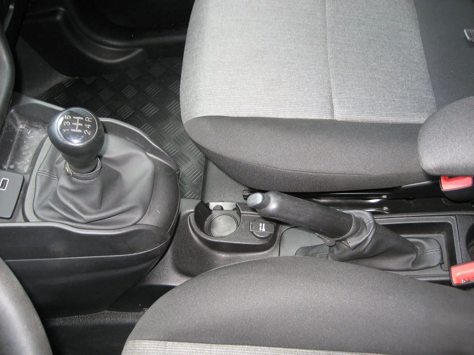 Vue rapprochée de la console centrale du Fiat Doblo Cargo blanc, montrant levier de vitesse manuel et frein à main.