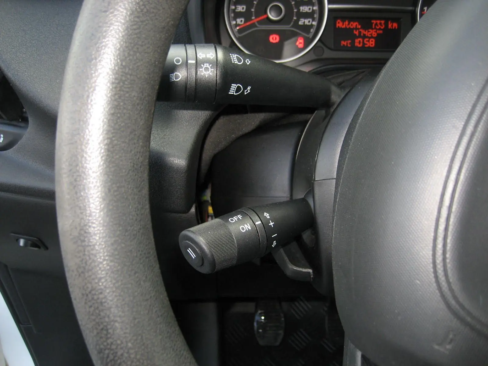 Gros plan sur le volant et le combiné d'instruments du Fiat Doblo Cargo blanc, avec affichage digital rouge et commandes au volant.
