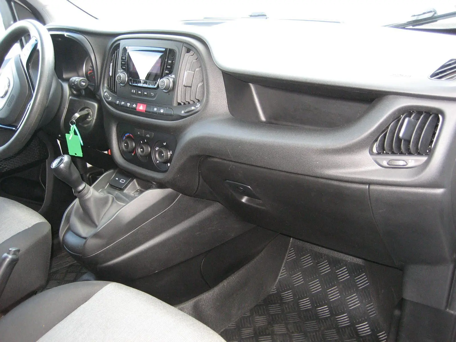 Vue intérieure côté passager du tableau de bord noir et gris du FIAT Doblo Cargo 2018 avec levier de vitesse manuel.