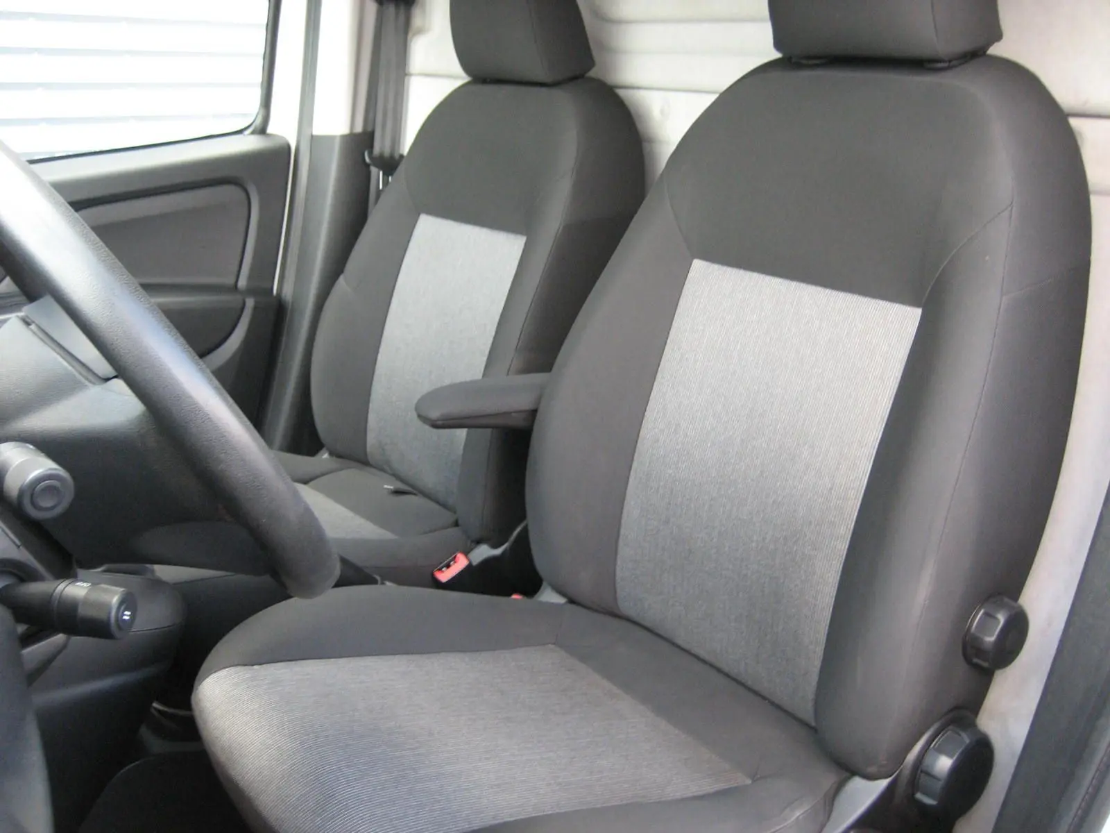 Vue intérieure rapprochée des sièges avant gris et noirs du Fiat Doblo Cargo 2018, avec accoudoir côté droit.