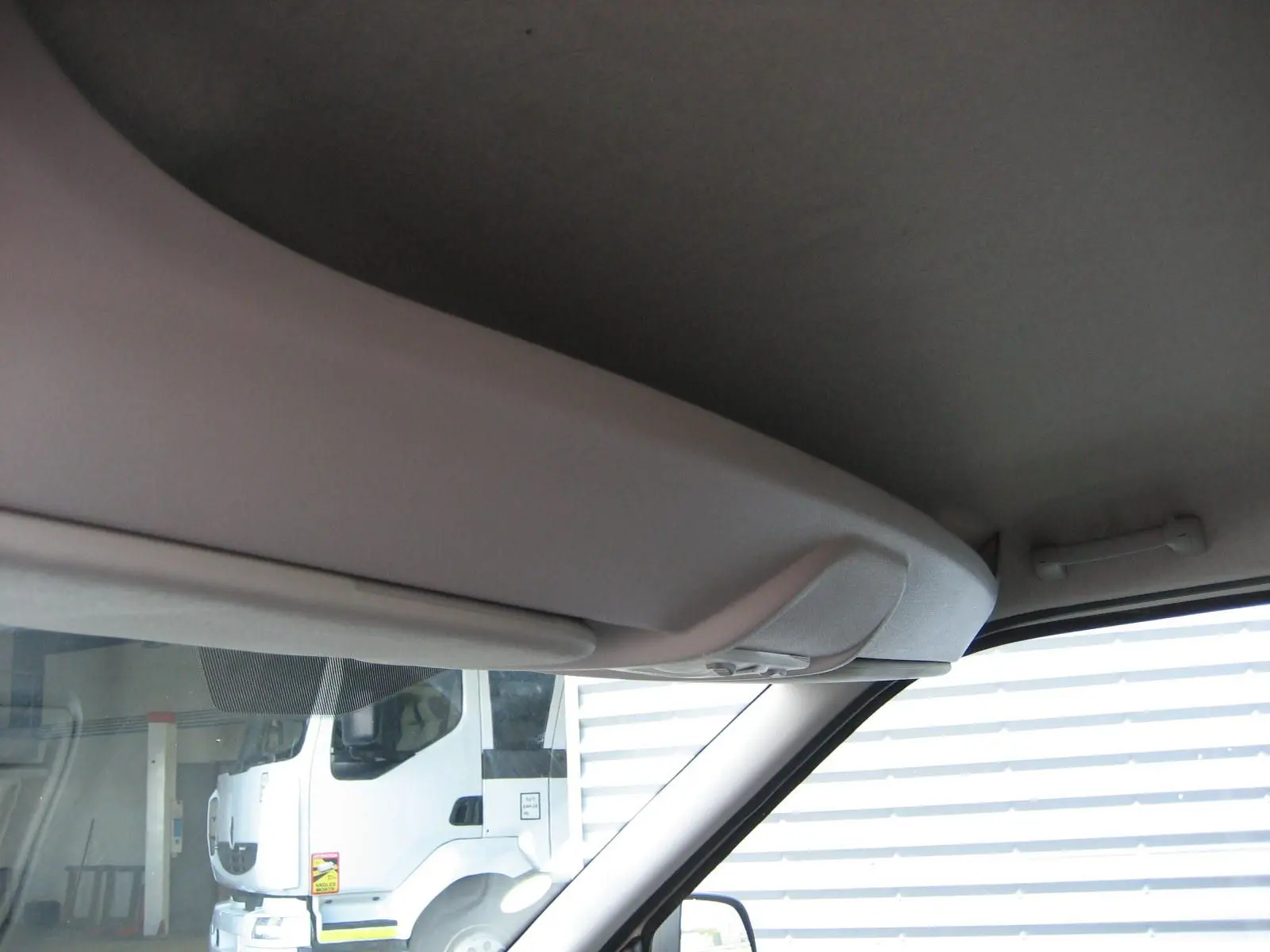 Vue intérieure côté passager du Fiat Doblo Cargo blanc 2018, montrant le plafond et pare-brise avec reflet extérieur.