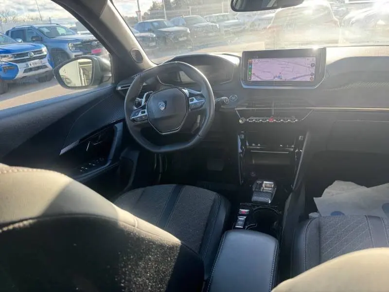 Vue intérieure avant du Peugeot 2008 Hybrid gris 2025, avec volant compact, écran tactile et cockpit numérique lumineux.
