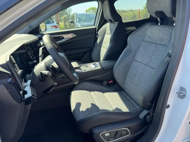 Vue intérieure côté conducteur du Renault Austral blanc nacré, sièges tissu gris clair avec console centrale moderne.
